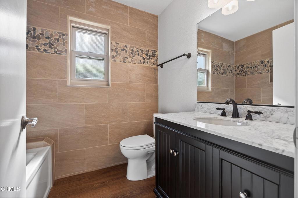 449 Reed Way Port Hueneme, CA 93041 - Photo 29 of 42 a bathroom with a granite countertop sink a toilet and a mirror