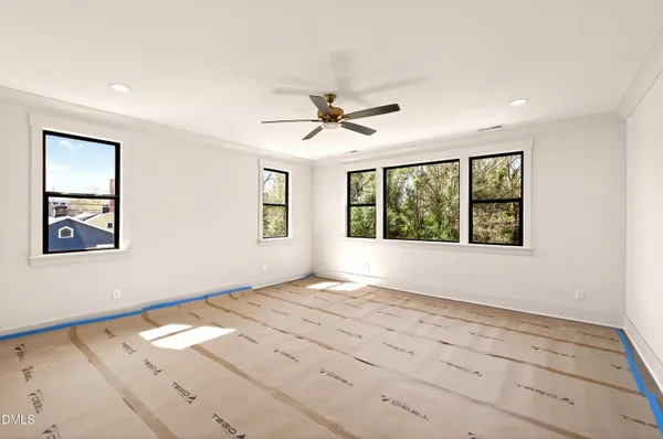 an empty room with windows and fan