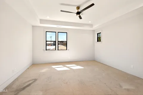 an empty room with windows and fan