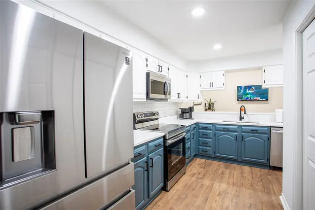 a kitchen with stainless steel appliances granite countertop a stove top oven a sink dishwasher a refrigerator and a oven with wooden floor