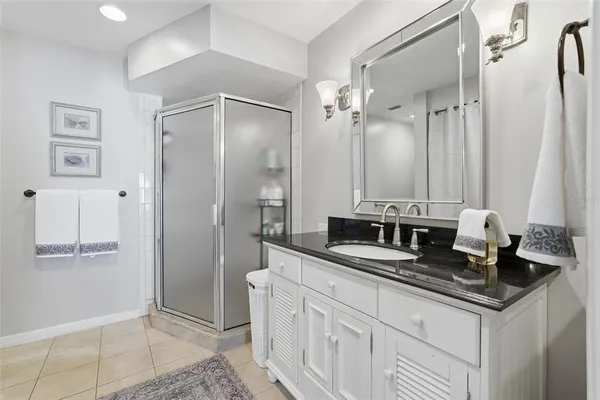 a bathroom with a granite countertop sink a mirror and a shower