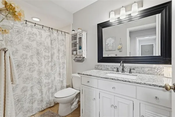 a bathroom with a granite countertop toilet sink and mirror