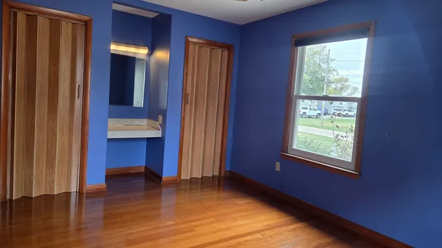 a view of empty room with wooden floor and fan