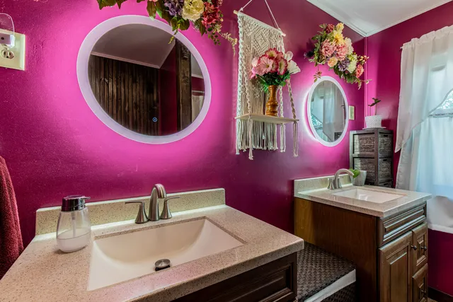 a bathroom with a sink a mirror and painting on the wall