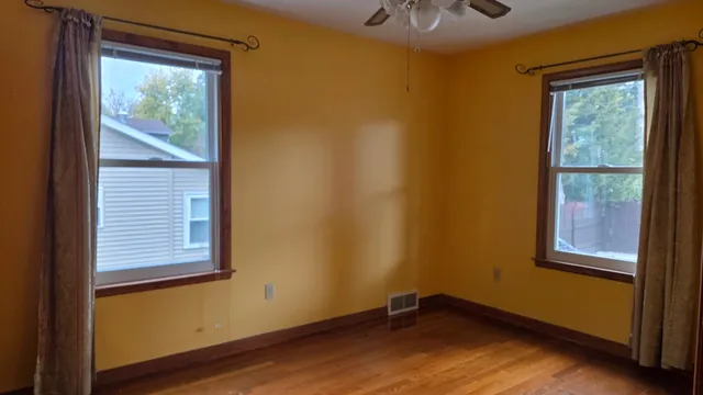 a view of an empty room with a window and wooden floor