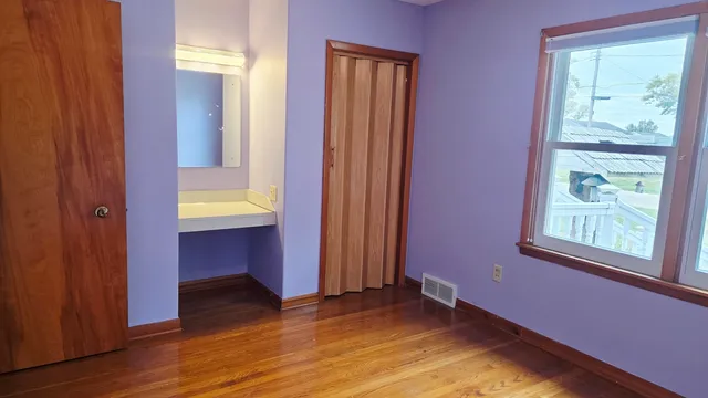 a view of an empty room with window and wooden floor