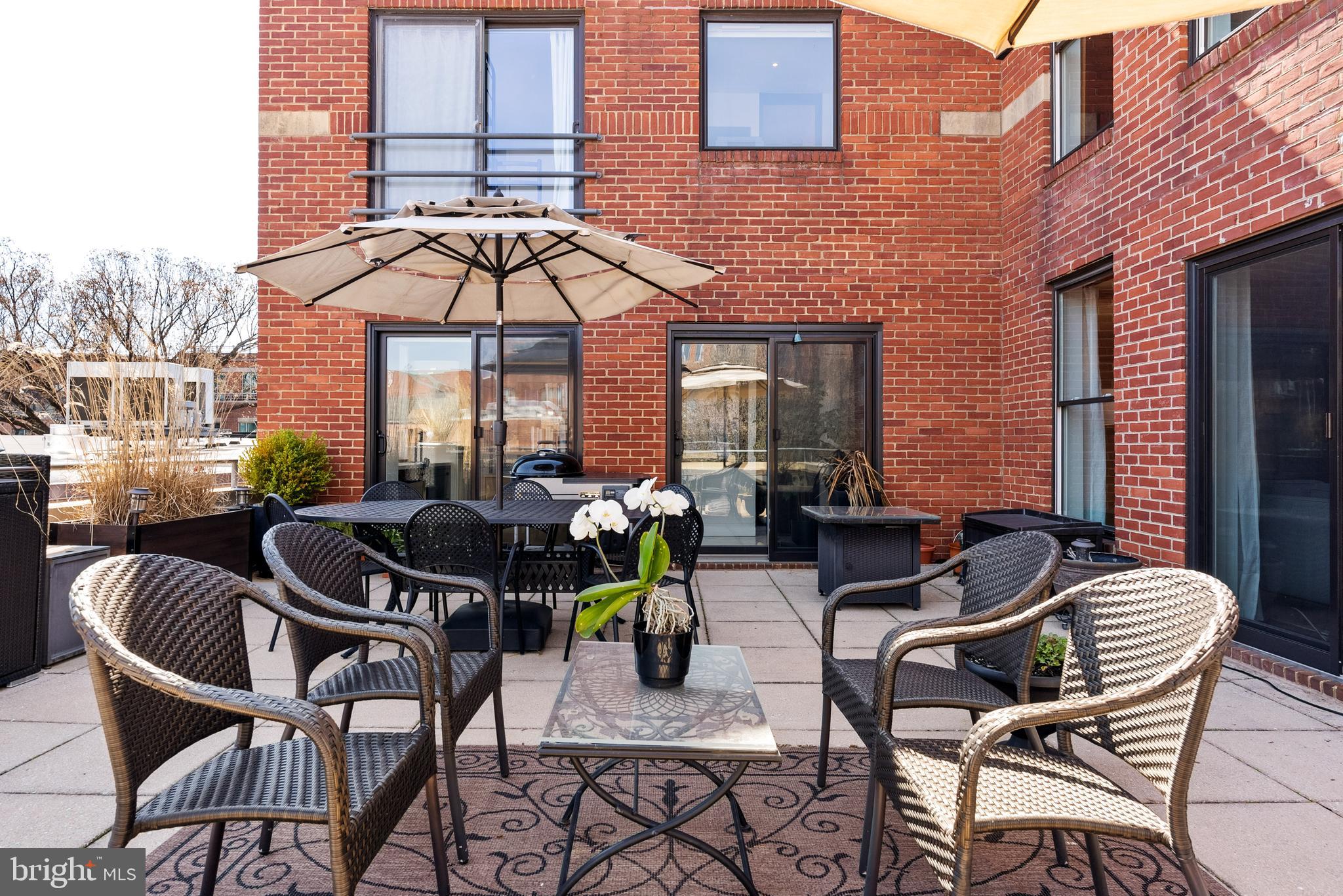 3210 Grace Street Northwest, Unit 304 Washington, DC 20007 - Photo 31 of 41 a view of a patio with dining table and chairs under an umbrella with a small garden