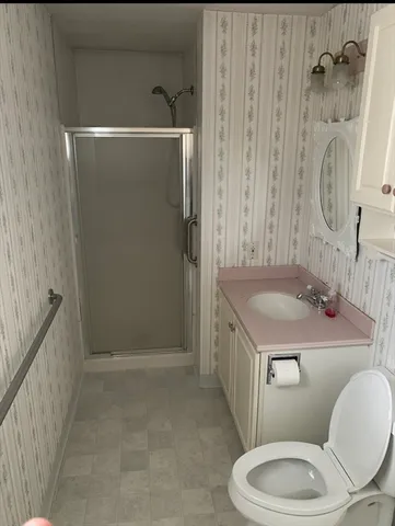 a bathroom with a granite countertop sink toilet a mirror and shower