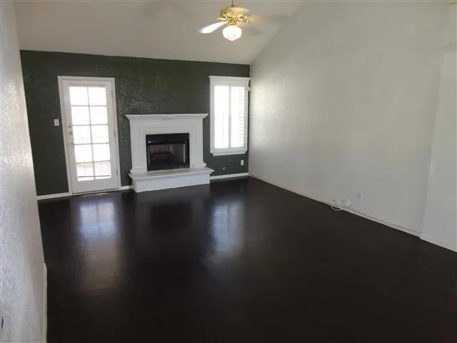 an empty room with wooden floor a fireplace and windows