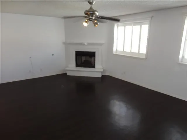 an empty room with wooden floor fireplace and windows