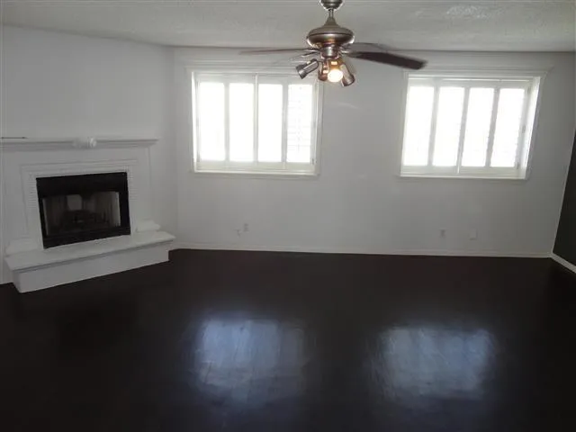 a view of wooden floor fire place and windows in a room