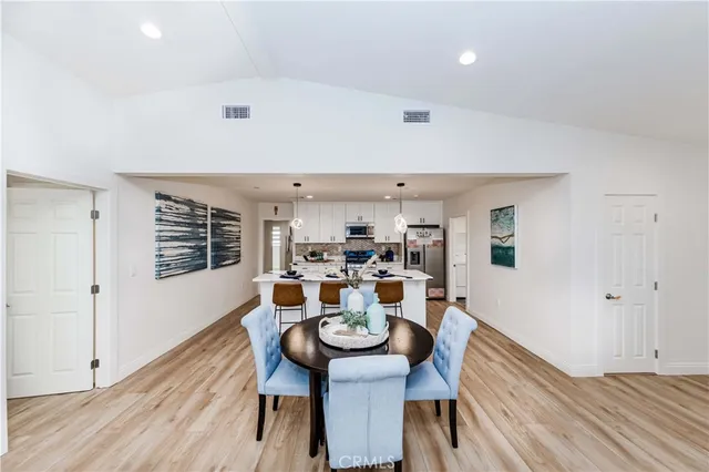 a large kitchen with stainless steel appliances a stove a sink dishwasher and a refrigerator with wooden floor