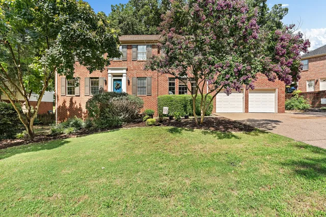 a front view of a house with a yard and trees
