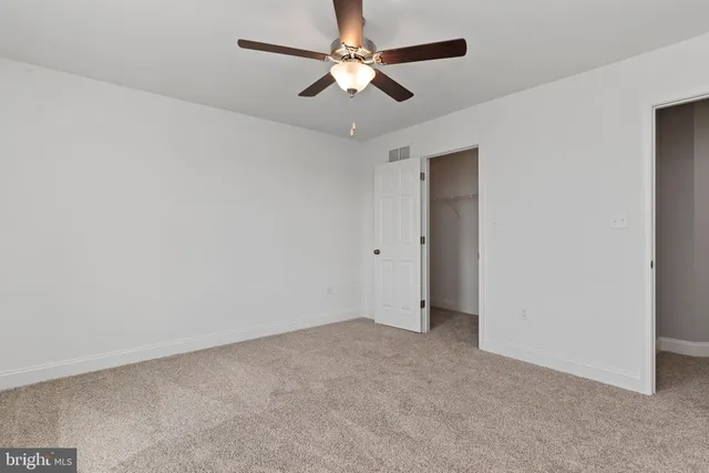 an empty room with a chandelier fan and a ceiling fan