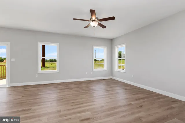 a view of an empty room with window and wooden floor