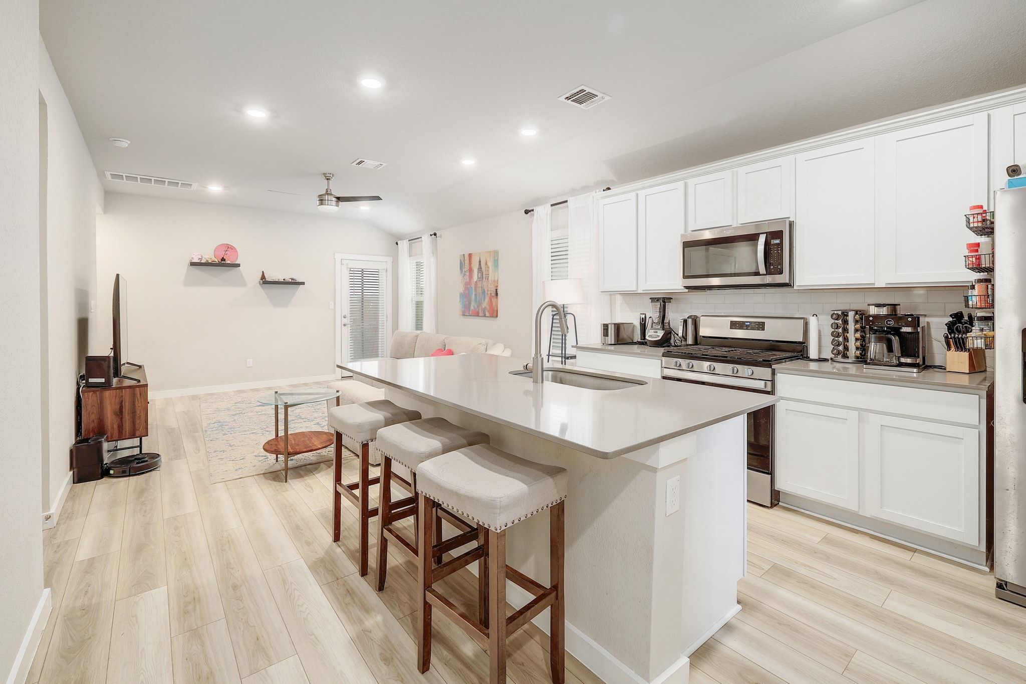 204 Halford Road Georgetown, TX 78633 - Photo 8 of 27 Kitchen featuring appliances with stainless steel finishes, light wood-style flooring, white cabinetry, lofted ceiling, and a kitchen breakfast bar