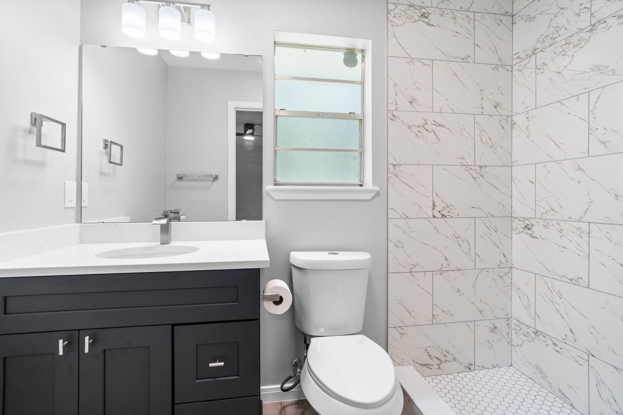 13400 Nicholson Road Conroe, TX 77303 - Photo 21 of 36 FULLY Remodeled primary bath with: new shower tiling, new toilet with cabinetry and brush nickel hardware.