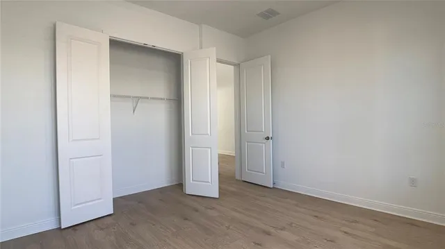an empty room with closet and wooden floor