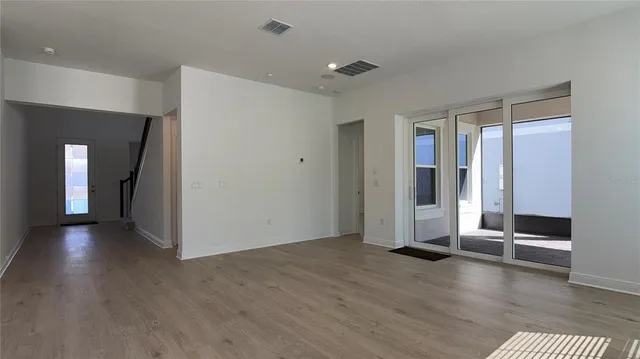 an empty room with wooden floor and windows
