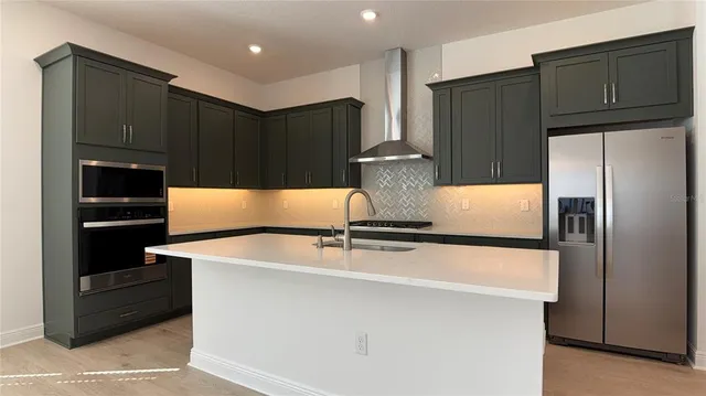 a kitchen with granite countertop a refrigerator and a stove top oven