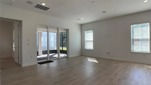 an empty room with floor to ceiling window and wooden floor