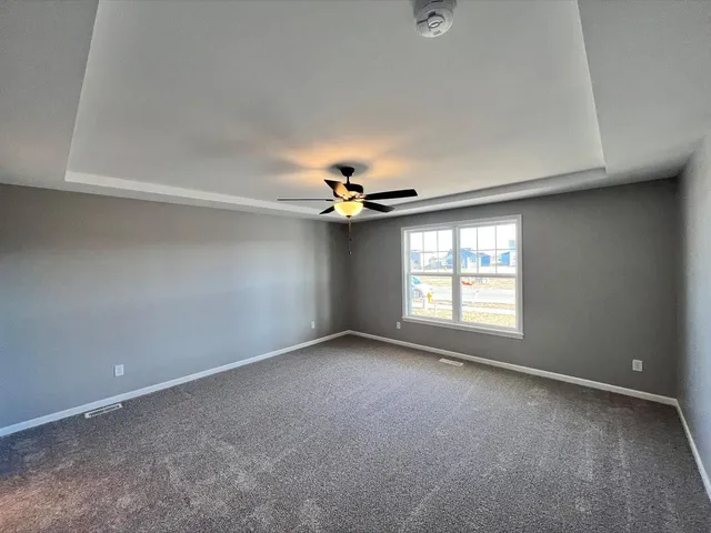an empty room with windows and fan