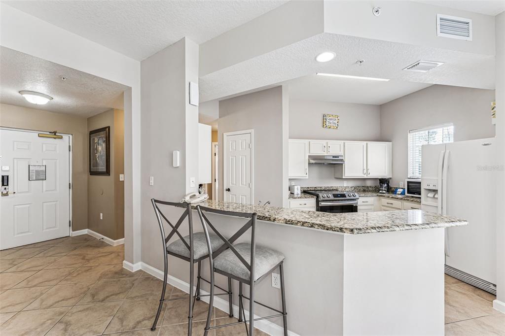 8801 Worldquest Boulevard, Unit 4108 Orlando, FL 32821 - Photo 12 of 85 a kitchen with stainless steel appliances granite countertop a stove top oven a sink a refrigerator and white cabinets