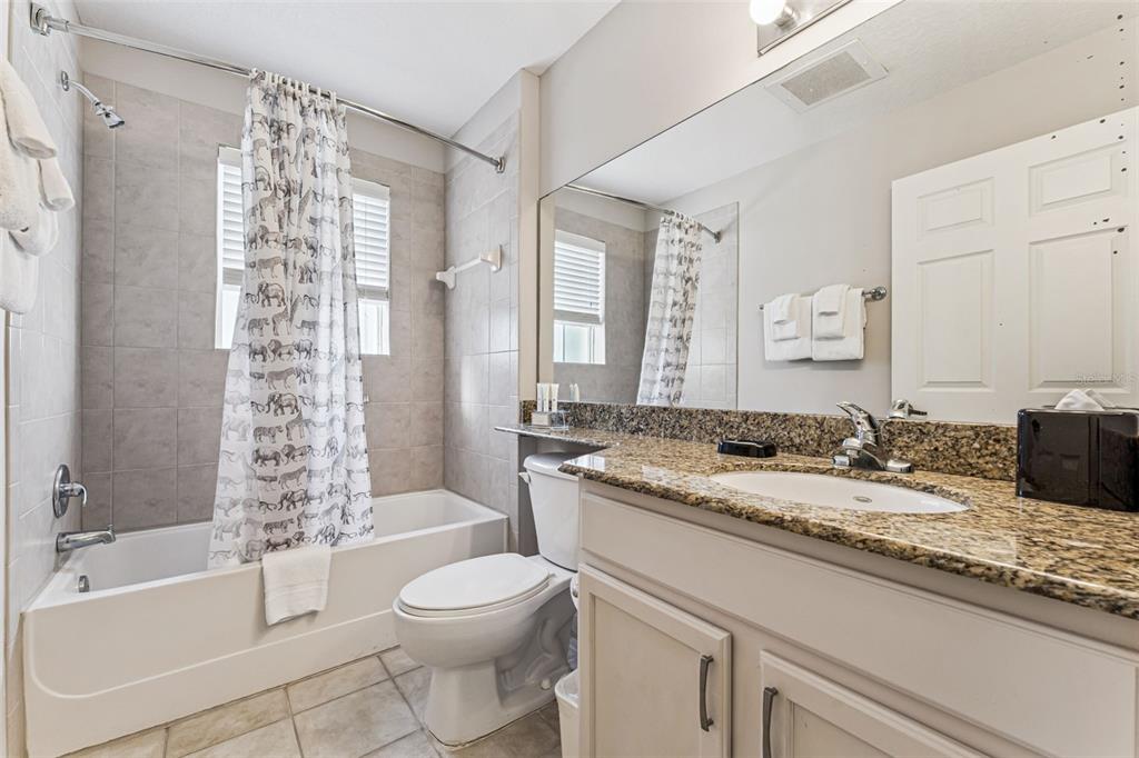 8801 Worldquest Boulevard, Unit 4108 Orlando, FL 32821 - Photo 24 of 85 a bathroom with a granite countertop toilet a sink a mirror a bathtub and shower