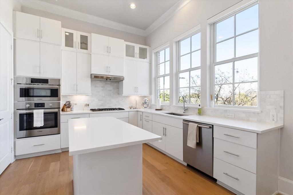 4129 Runyon Road Addison, TX 75001 - Photo 9 of 38 Kitchen with white cabinetry, crown molding, glass insert cabinets, a center island, and recessed lighting