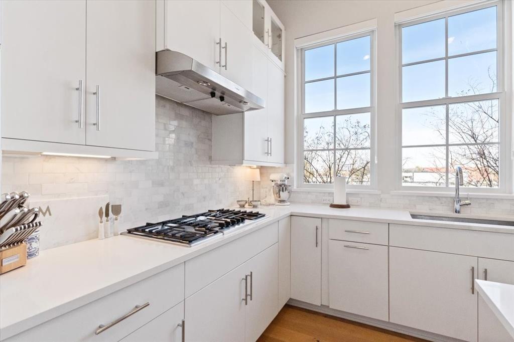 4129 Runyon Road Addison, TX 75001 - Photo 10 of 38 Kitchen with glass insert cabinets, white cabinetry, stainless steel gas cooktop, light wood-style floors, and backsplash