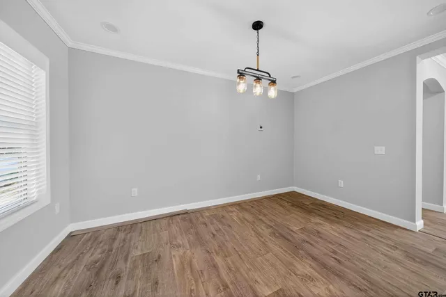 a view of empty room with wooden floor fan and window