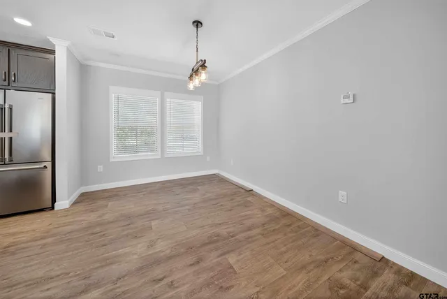 an empty room with wooden floor cabinet and windows