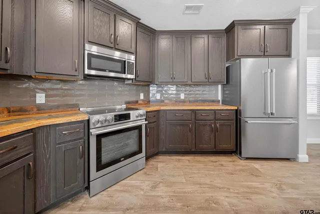 a kitchen with stainless steel appliances granite countertop a stove a sink dishwasher a refrigerator and a microwave