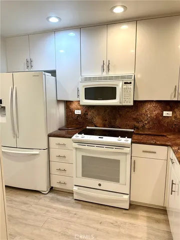 a kitchen with granite countertop white cabinets and stainless steel appliances