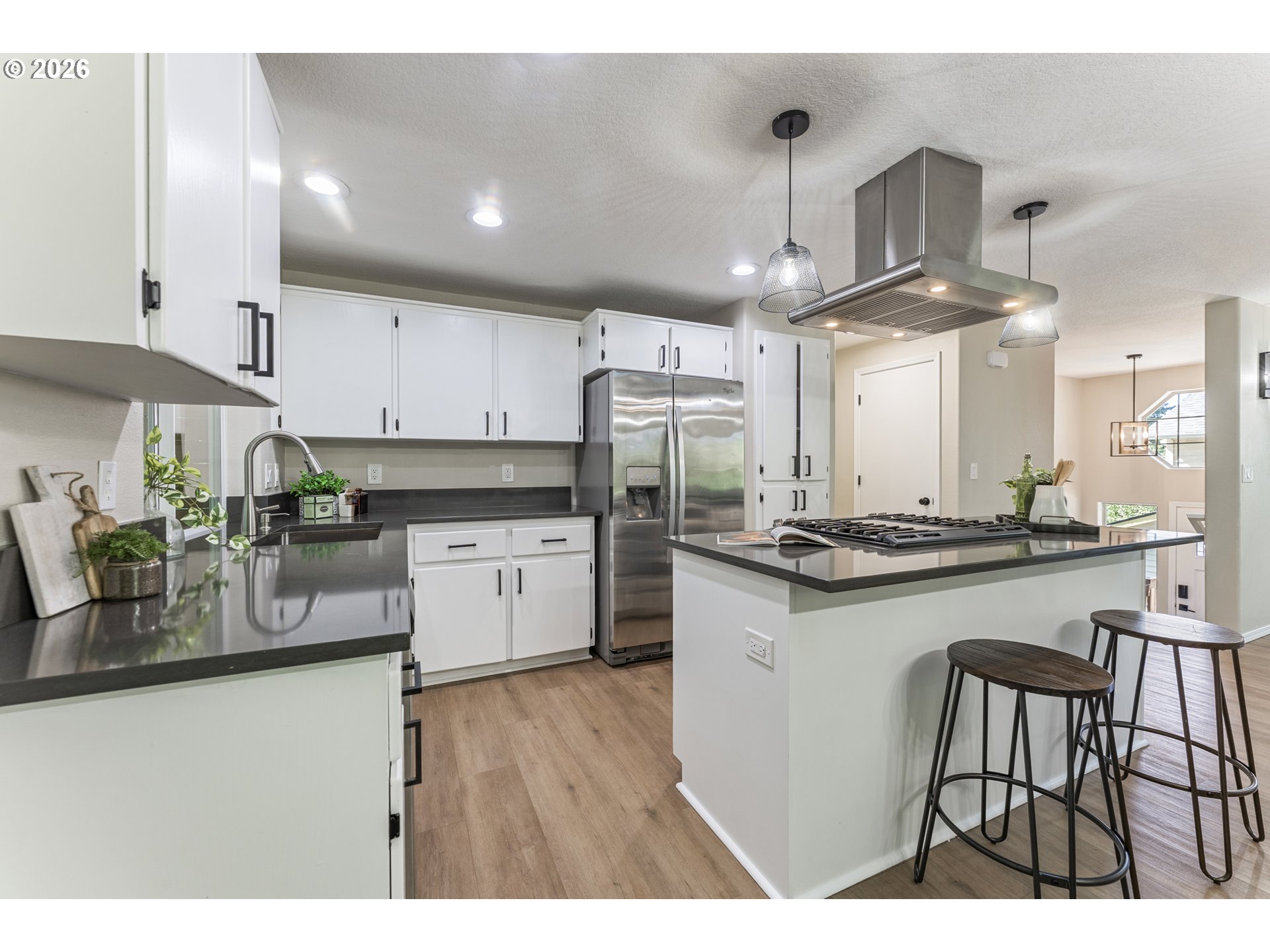 4024 Southeast 154th Place Portland, OR 97236 - Photo 5 of 43 a kitchen with stainless steel appliances kitchen island granite countertop a refrigerator a stove a sink dishwasher and white cabinets with wooden floor