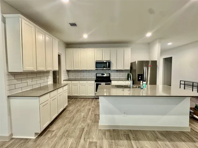a large kitchen with stainless steel appliances granite countertop a sink stove and refrigerator