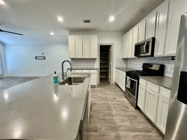 a view of a kitchen with kitchen island a sink stainless steel appliances and cabinets