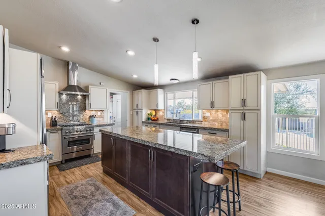 a kitchen with stainless steel appliances granite countertop a refrigerator a sink dishwasher a stove and white countertops with wooden floor