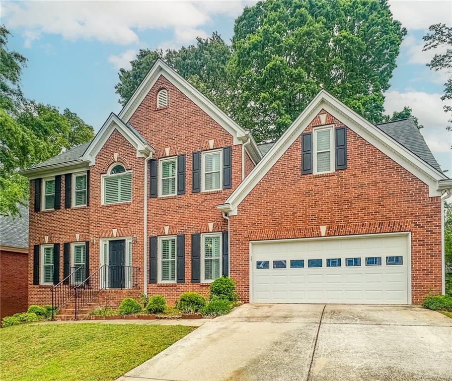 1485 Oglethorpe Run Lane Suwanee, GA 30024 - Photo 2 of 18 a front view of a house with a yard and garage