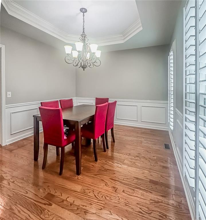 1485 Oglethorpe Run Lane Suwanee, GA 30024 - Photo 7 of 18 a view of a dining room with furniture a chandelier and wooden floor