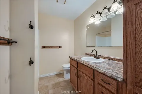a bathroom with a granite countertop sink a toilet and mirror