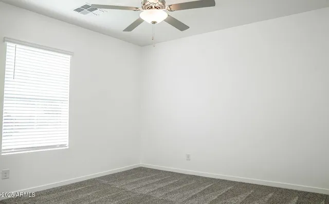 an empty room with a window and a fan