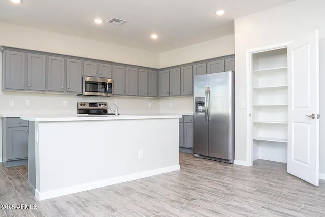 a kitchen with stainless steel appliances granite countertop a refrigerator a sink a stove a microwave and wooden cabinets