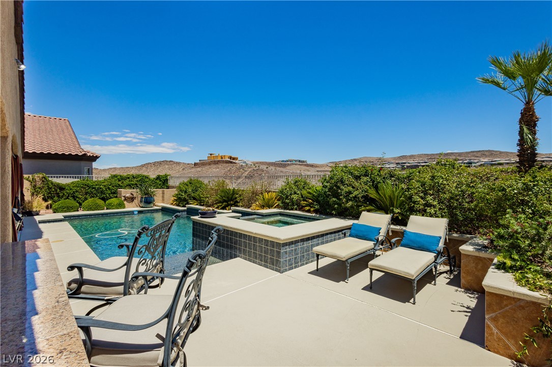 2256 Dogwood Ranch Avenue Henderson, NV 89052 - Photo 48 of 51 An inviting backyard oasis offers a sparkling pool with an integrated spa, set against a distant mountain backdrop.