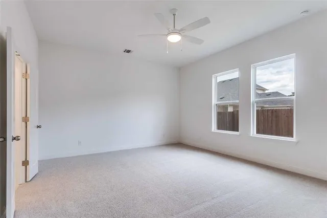 an empty room with windows and ceiling fan