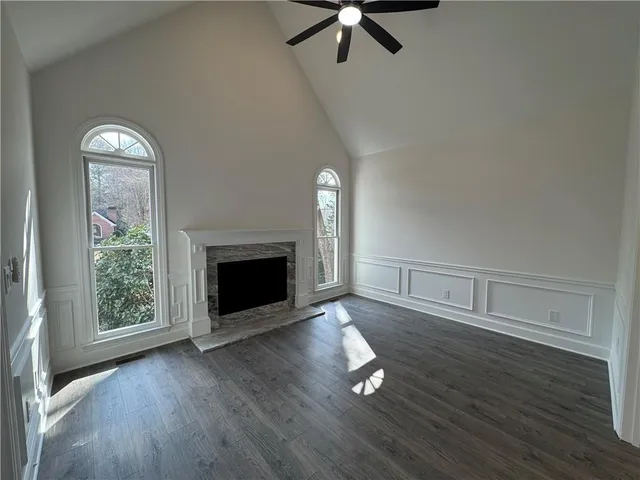an empty room with wooden floor fireplace and windows