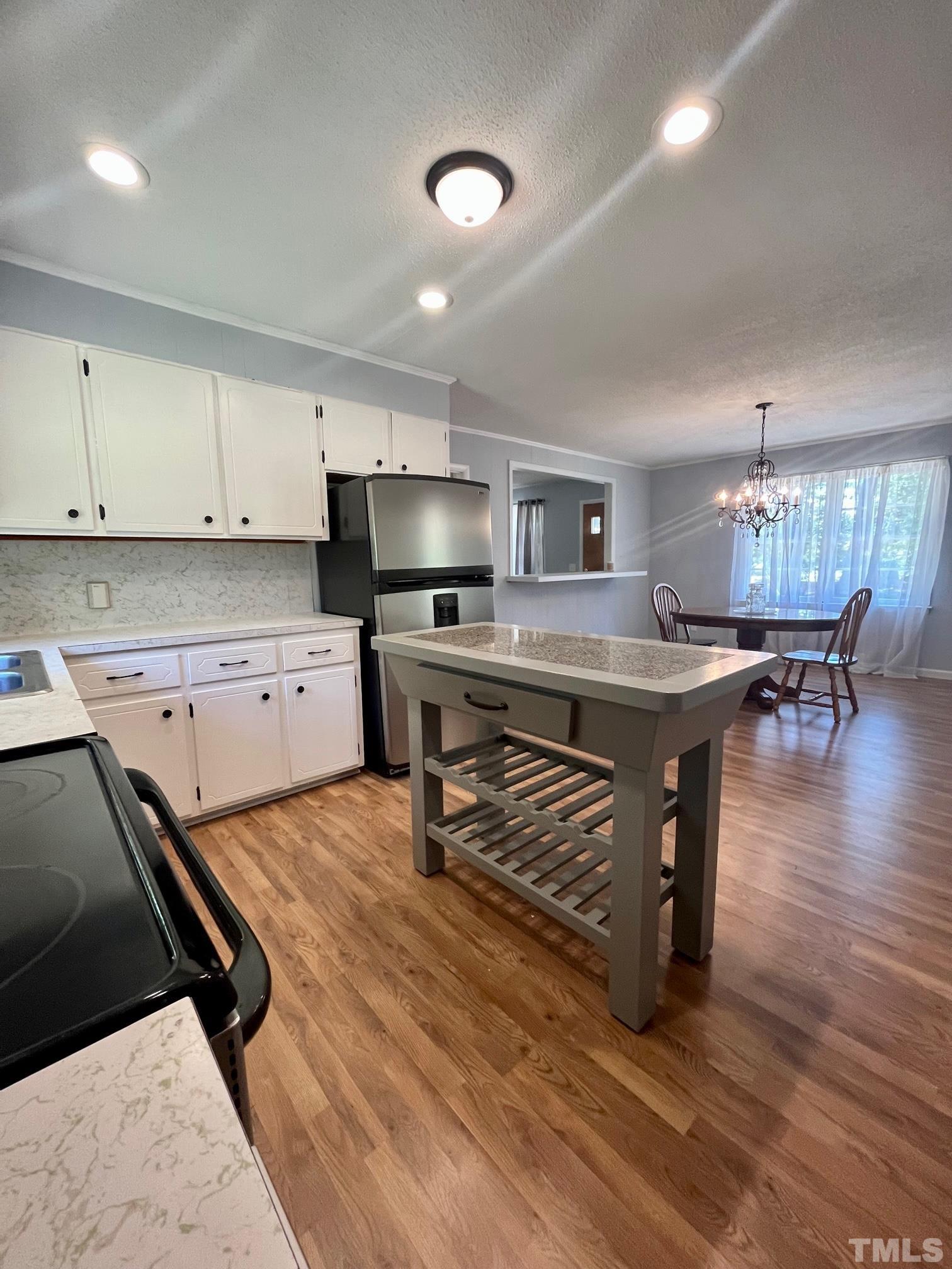 2342 Mitchell Road Angier, NC 27501 - Photo 9 of 10 a kitchen with stainless steel appliances a stove a sink a refrigerator white cabinets and wooden floor