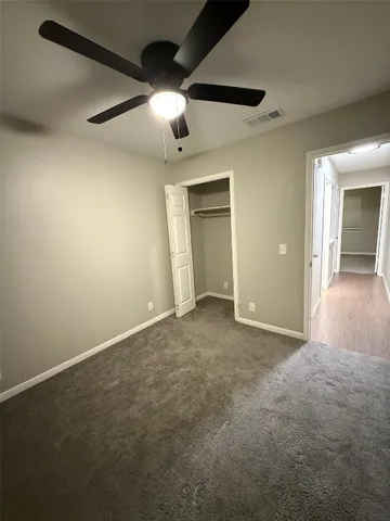 an empty room with ceiling fan and windows