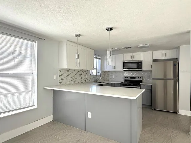 a kitchen with stainless steel appliances a refrigerator a stove a sink and white cabinets