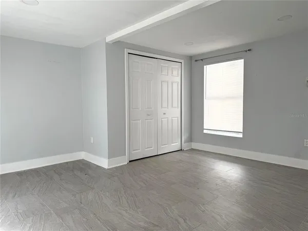 a view of an empty room with wooden floor and a window